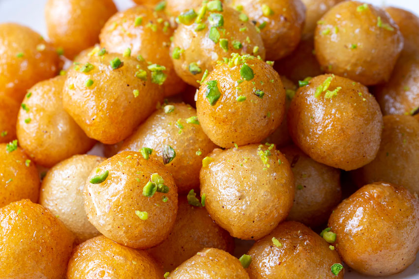 Fried dough balls scattered with chopped pistachios