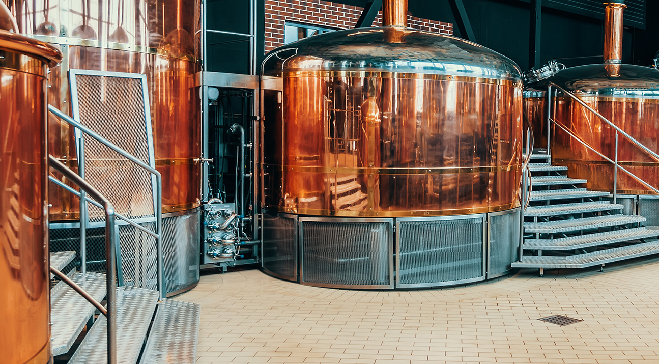 Large brass brewing vessels with steps in between them.