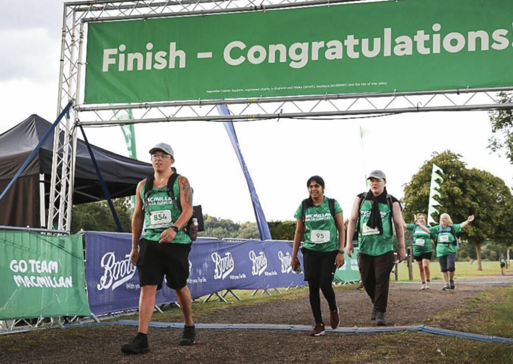 Three people in green shirts and bibs cross the finish line under a banner that says Finish - Congratulations