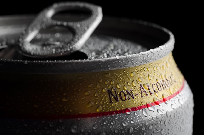 An opened can of non-alcoholic beer fresh from the fridge with condensation across its silver and yellow surface.
