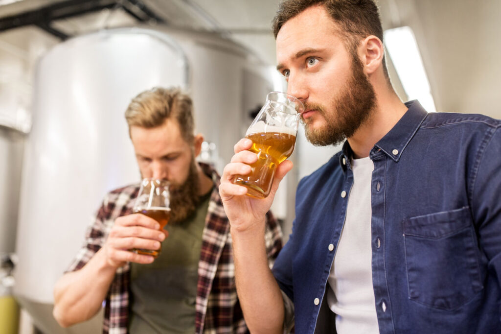 Two men sniffing amber coloured beer from pint glasses